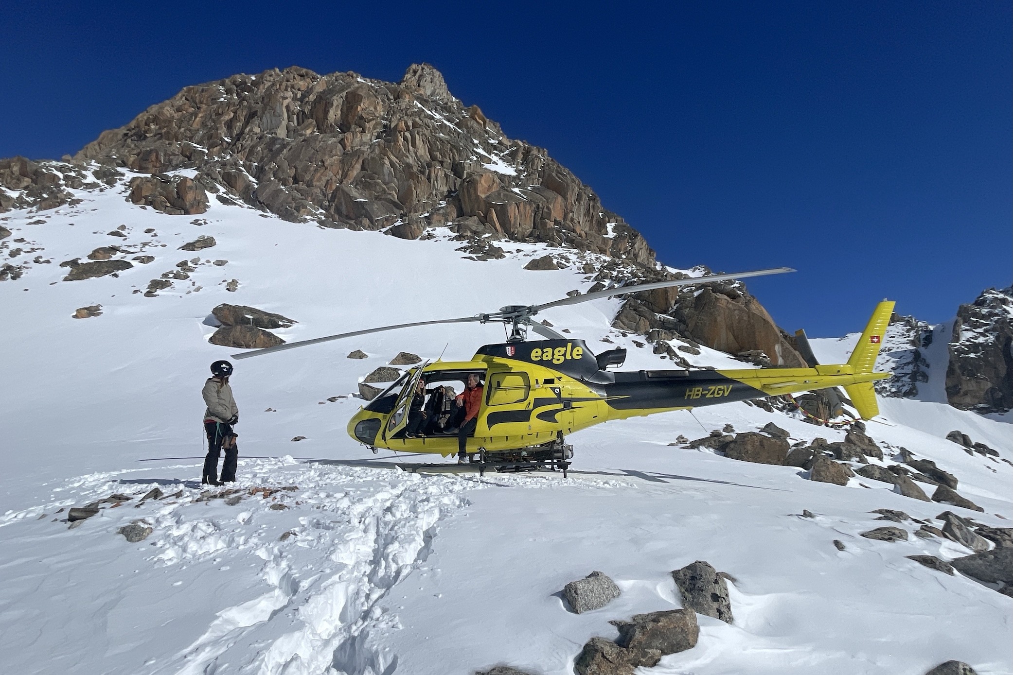 Helicopter parked in deep snow at high altitude during a private heli-ski safari in the Alps