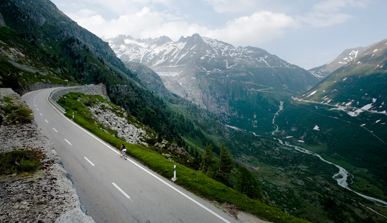 alpine-mountain-pass-swissskisafari-biking-safari-1300x750 A dramatic Alpine mountain pass stretching into the distance under a wide open sky