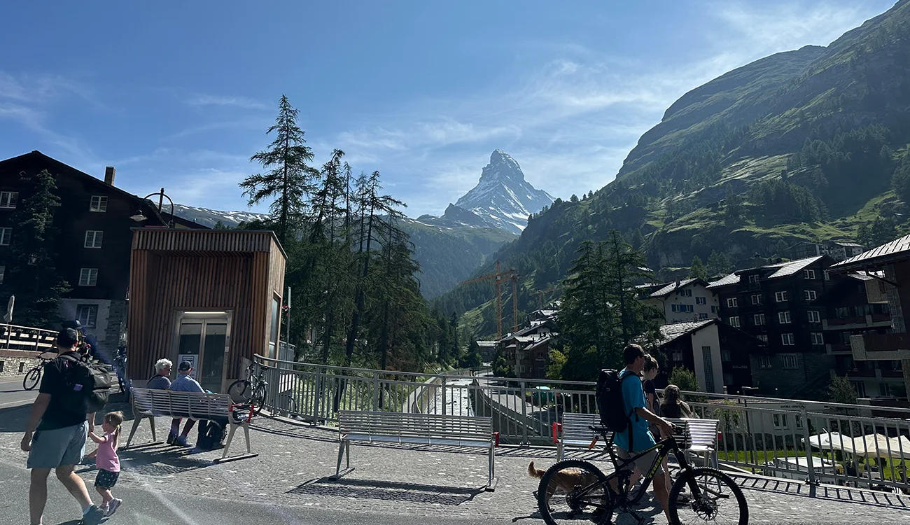 bikes-parked-matterhorn-view-swissskisafari-luxury-biking-safari-alps-1300x750 Two bicycles parked on an Alpine road with the iconic Matterhorn rising sharply into a clear blue sky