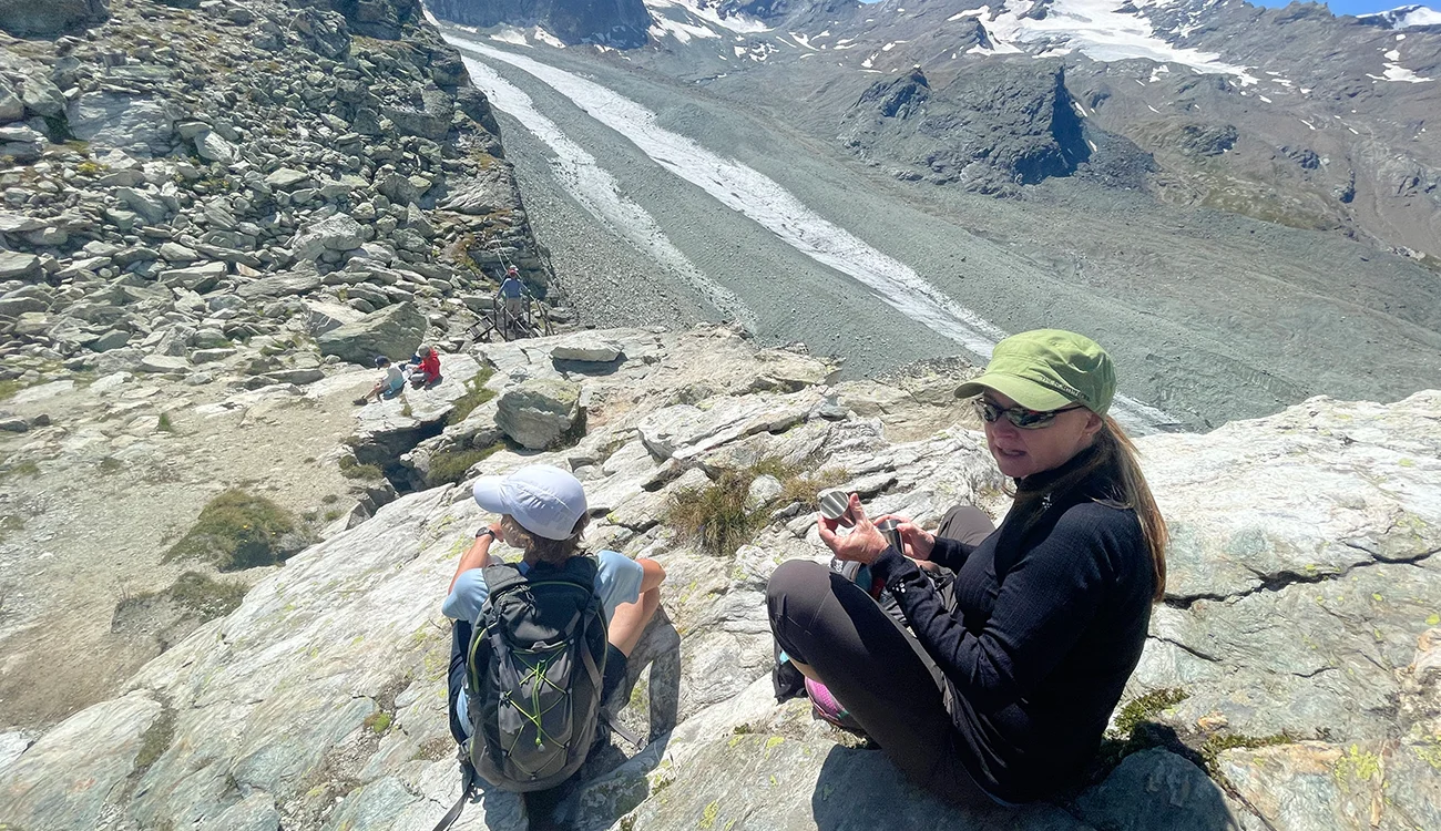 Two hikers sitting and taking in the view above a glacier during a heli-hiking safari in the Alps