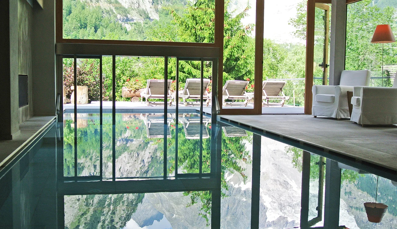 A serene indoor swimming pool in a luxury Alpine hotel, with warm lighting and refined finishes