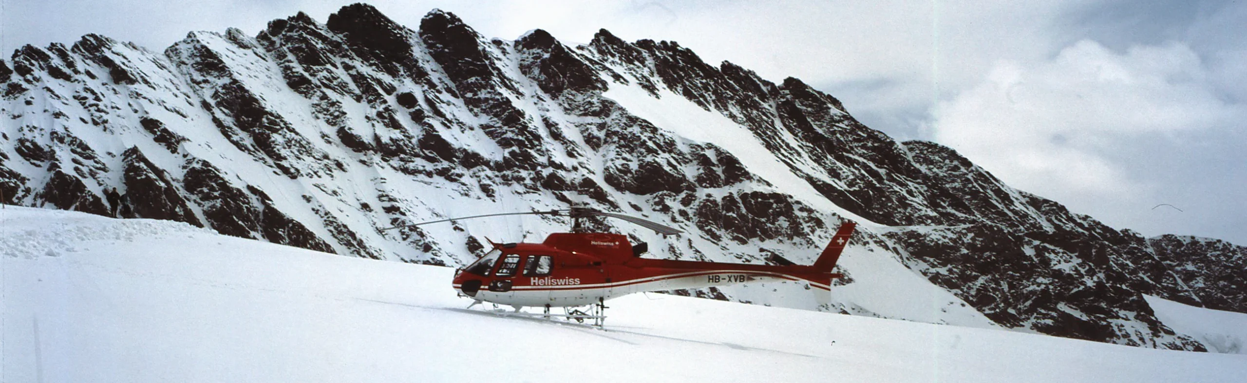 luxury-summer-safari- heli-hiking-Alps Helicopter landed on a glacier with mountain peaks in the background