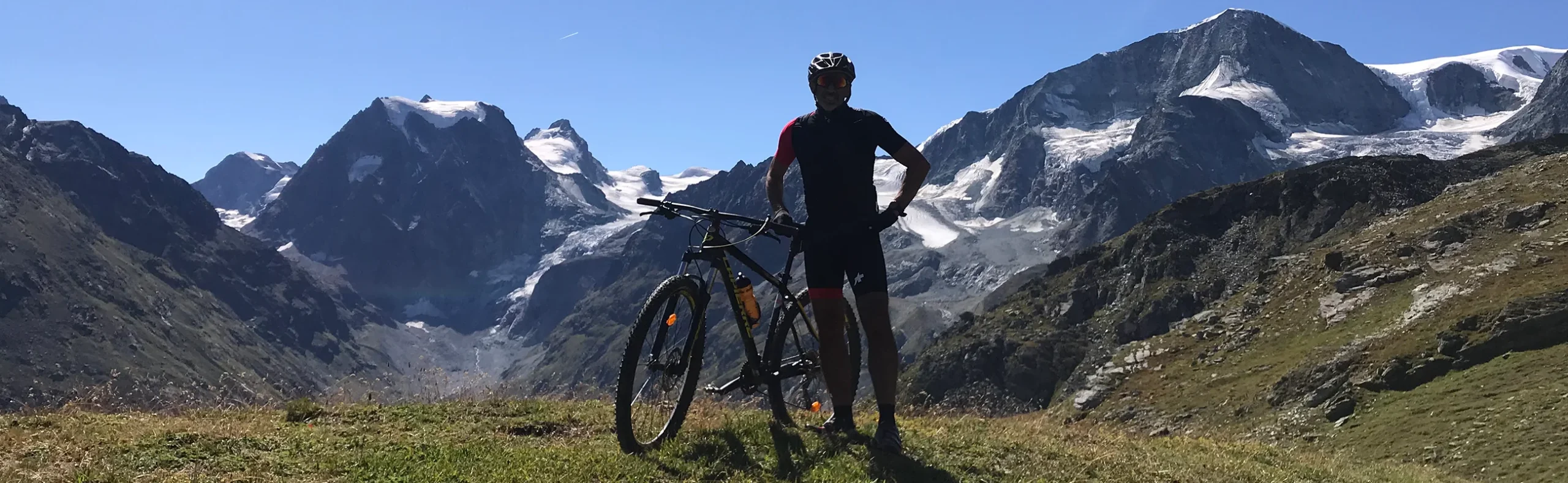 man-riding-e-bike-trail-mountain-summits-2600x800 Man riding an e-bike on a trail with mountain summits in the background