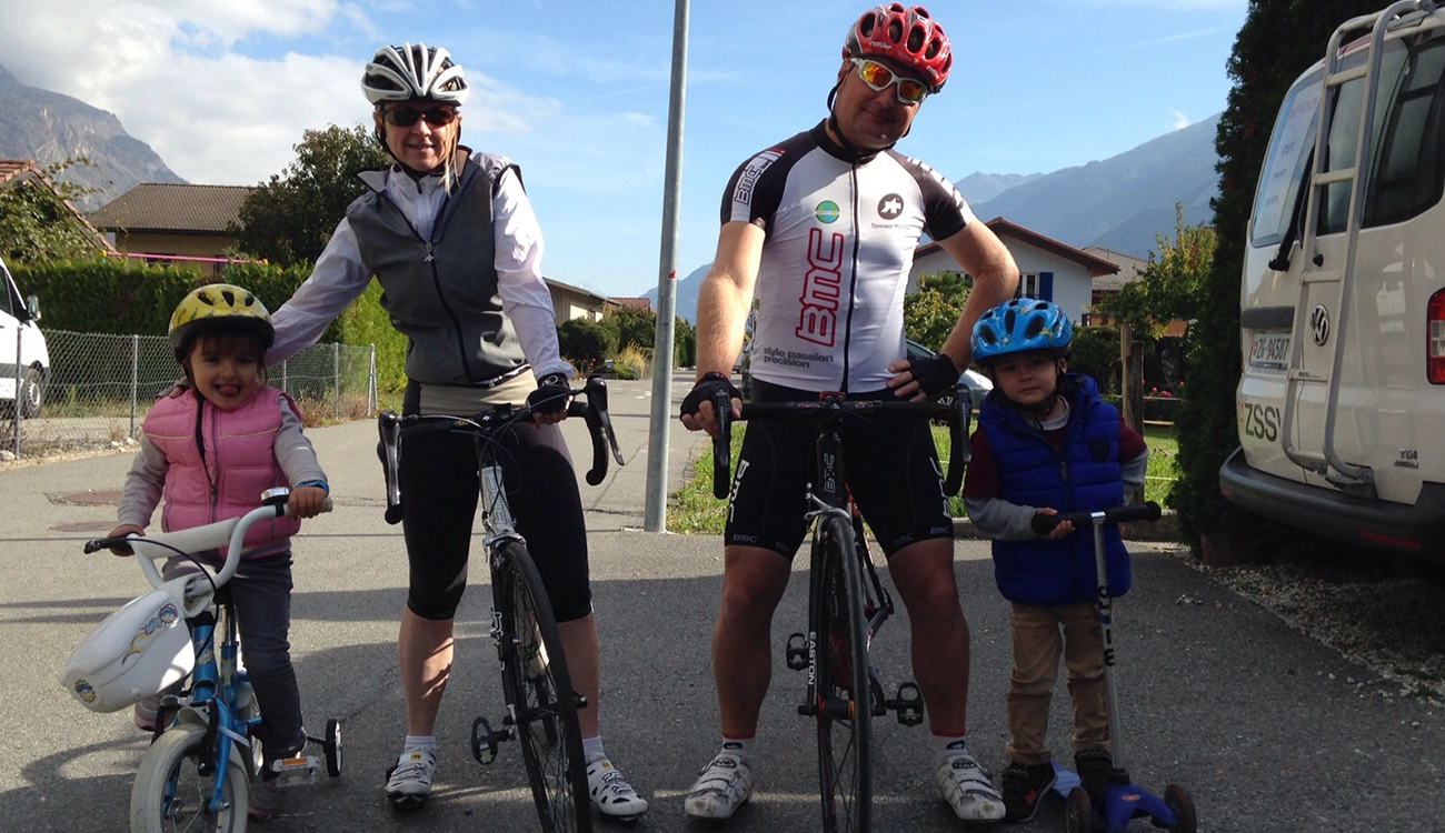 road-cyclists-local-children-alpine-village-swissskisafari-luxury-biking-safari-alps-1300x750 Two cyclists on road bikes pause as local children wave hello on a quiet Alpine village road