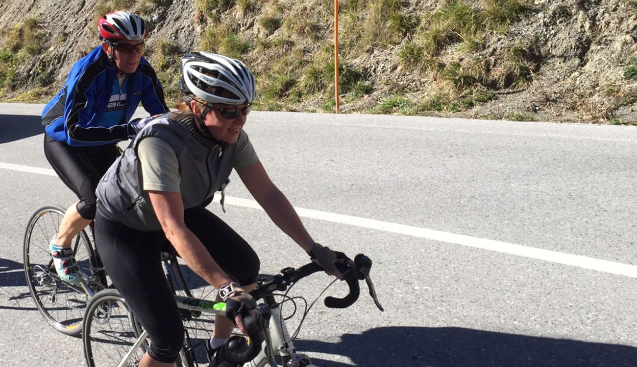 road cyclists ride together on an open Alpine road-1300x750 road cyclists ride together on an open Alpine road surrounded by mountain scenery