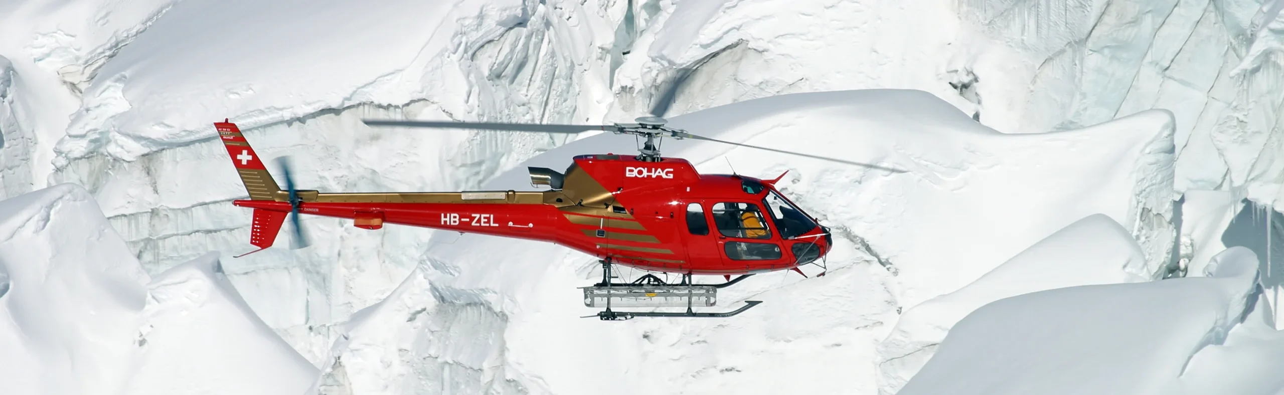 Heli-Ski Safari - Glacier Terrain - Alps Aerial view of a helicopter flying low over glacier terrain during a cross-border heli-ski safari in the Alps