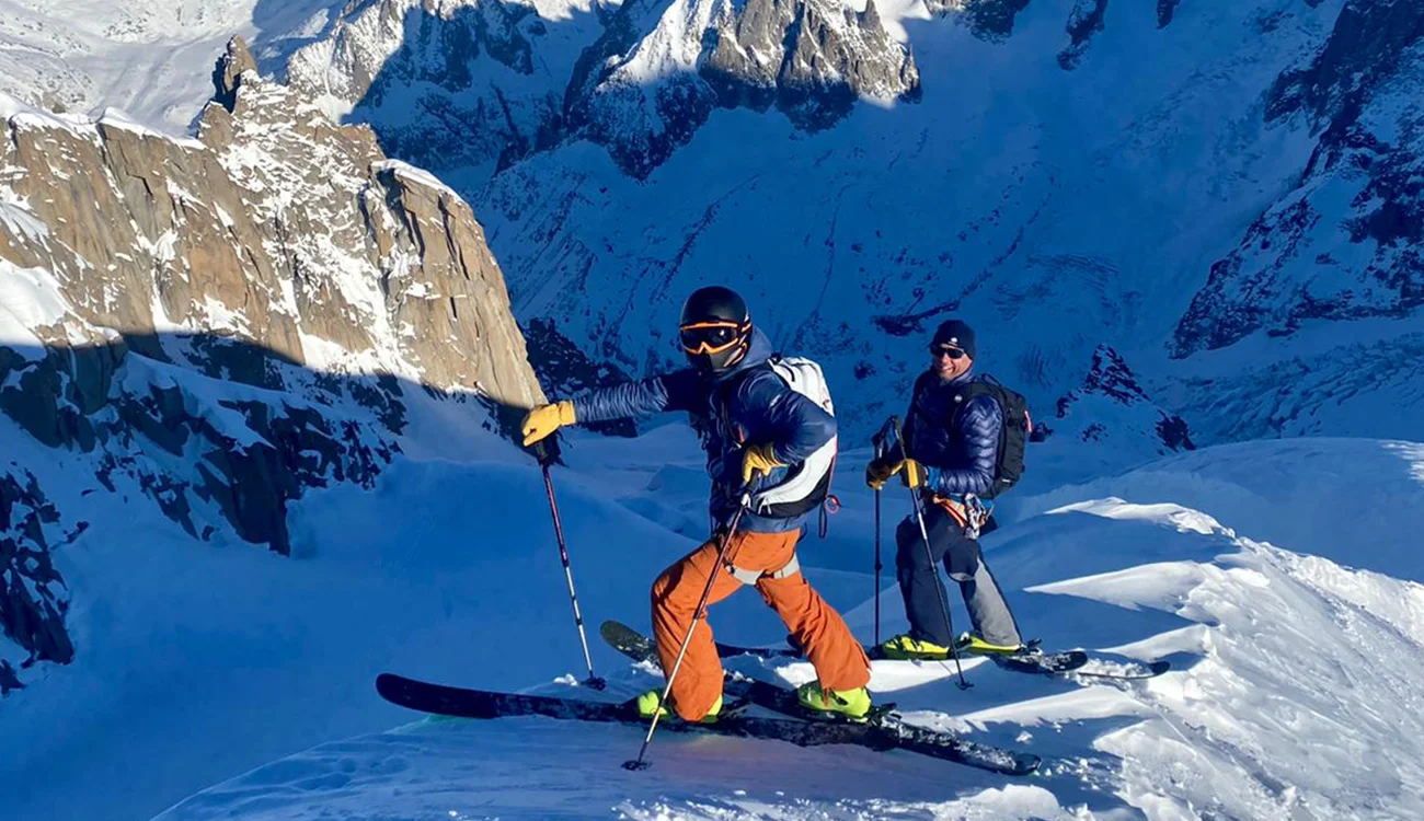 Heli-Ski Safari - Guided Off-Piste - Alps Two skiers on a snow ridge during a guided off-piste day before a heli-ski safari