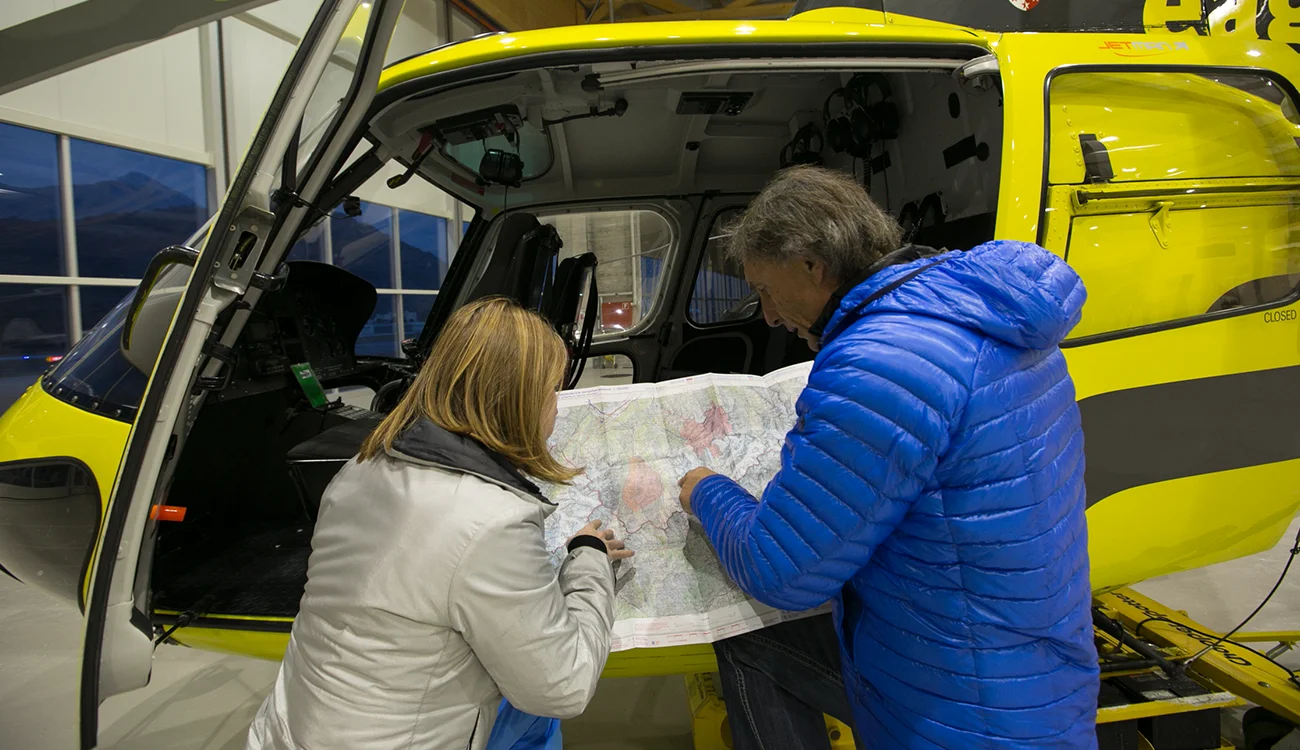 Heli-Ski Safari - Pilot Planning - Alps Pilot studying a map in front of a helicopter in the hangar during a heli-ski safari