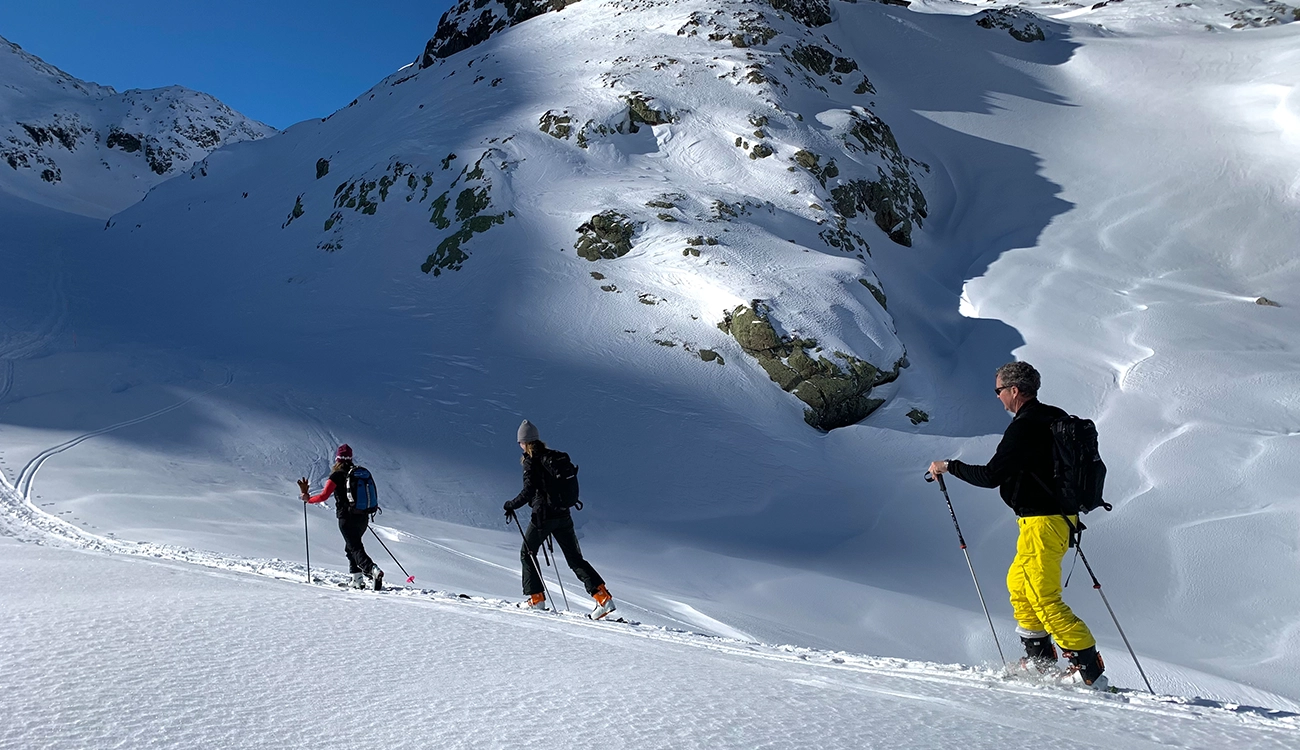 Winter Ski Safari - Ski Touring - Switzerland-Italy Border Three skiers ski touring toward the Switzerland-Italy border during a winter ski safari in the Alps