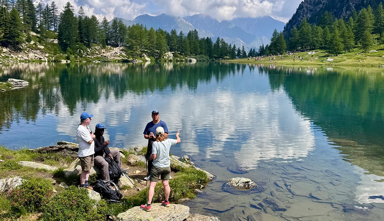 corporate-retreat-hikers-alpine-lake-switzerland Executive team standing beside a turquoise alpine lake during a private corporate hiking retreat in Switzerland