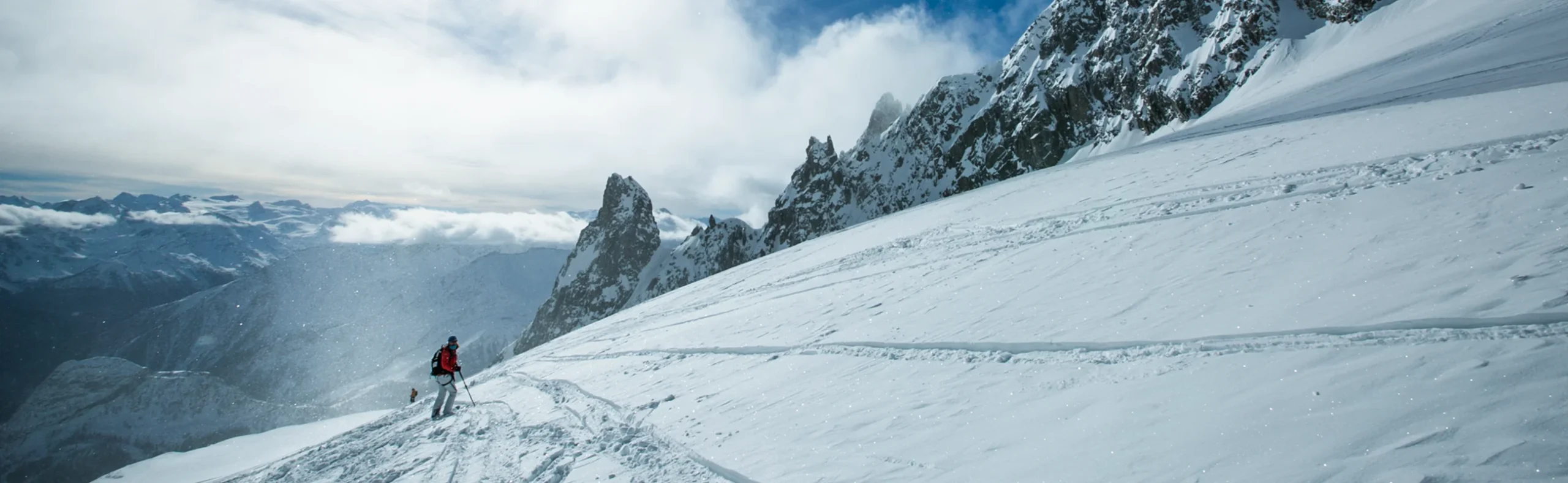 Skier crossing a vast glacier under blue sky