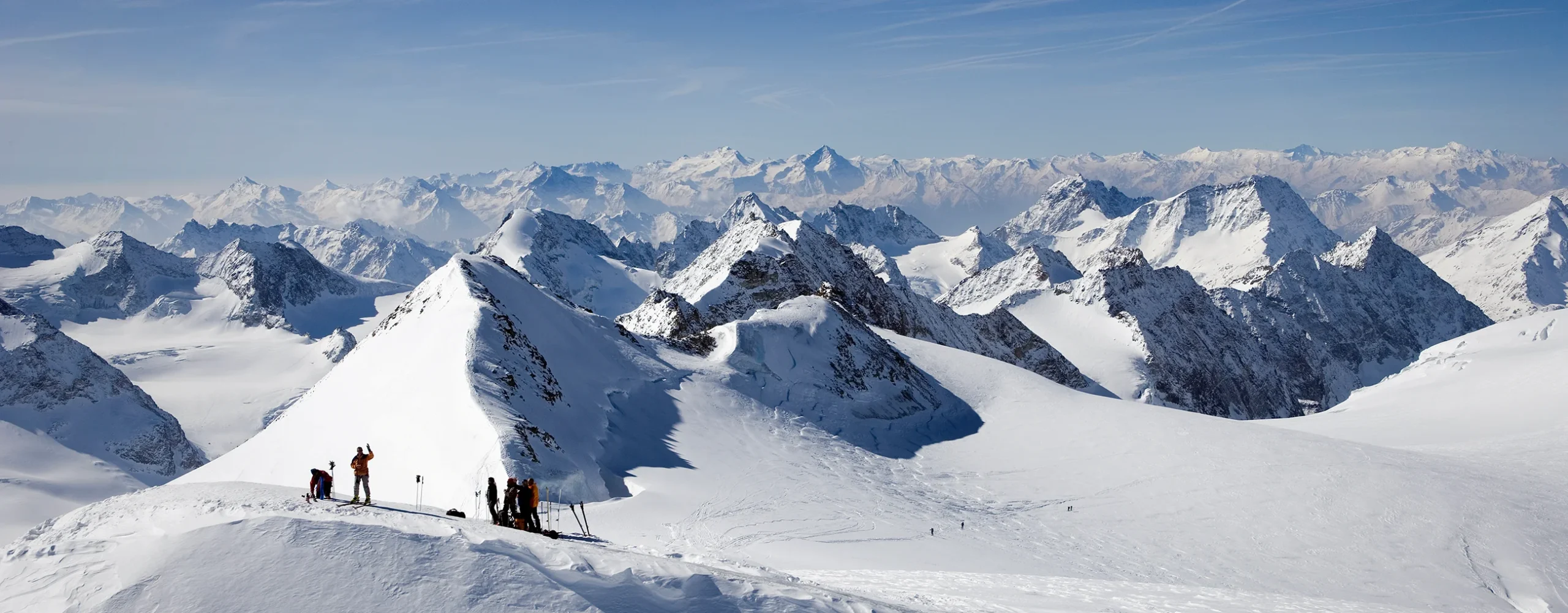 Panoramic aerial view of a heli-skiing drop during a private guided safari across the Alps, mountain range spread out beyond the helicopter