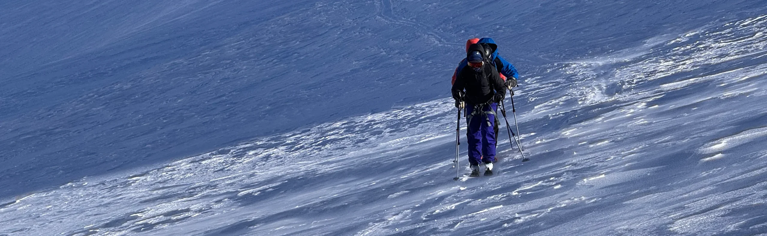 ski-tourers-crossing-firm-spring-snow Group of ski tourers crossing a slope of firm, wind-packed snow