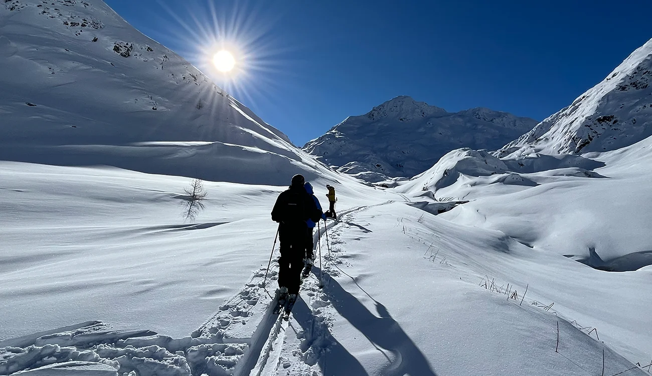 ski-touring-hiking-to-switzerland-italy-border Ski tourers hiking toward the border between Switzerland and Italy during a guided ski touring safari